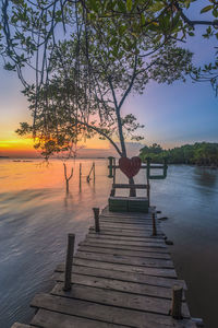 Pier over lake against sky during sunset