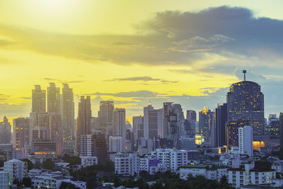 Modern buildings in city against sky during sunset