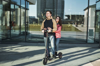 Loving young millennials having fun walking on an electric scooter