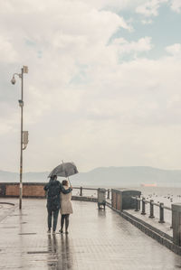 Rear view of man with umbrella on street during rainy season