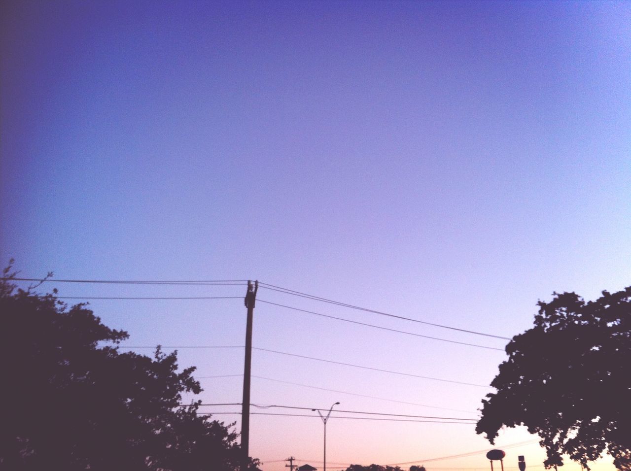 power line, clear sky, low angle view, electricity pylon, copy space, electricity, power supply, cable, connection, tree, silhouette, blue, power cable, technology, fuel and power generation, street light, high section, built structure, dusk, outdoors