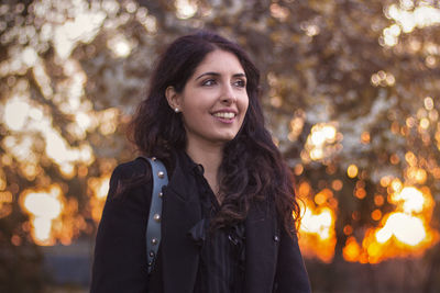 Portrait of smiling young woman standing against trees