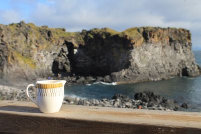 Coffee in cup at beach against sky