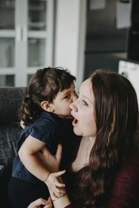 Mother and girl looking at camera while standing outdoors