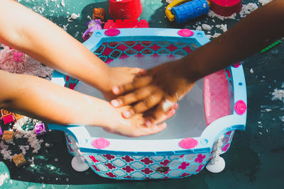 Cropped image of people washing hands in tub