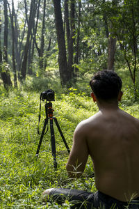 Millennial guy meditating with trainer online via tablet ipad connection, in the forest, broadcastin