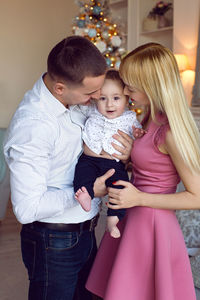 Parents and son are a child's son at the christmas tree at home