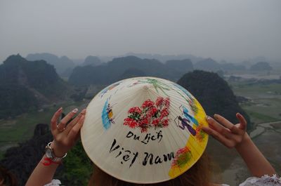 Midsection of woman holding umbrella against mountain