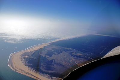 Aerial view of sea and mountains against blue sky