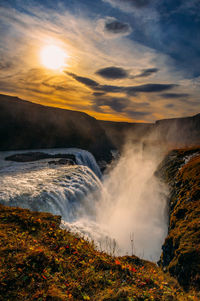 Scenic view of waterfall against sky during sunset