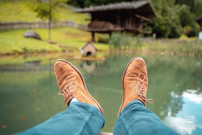 Low section of man wearing shoes against lake 