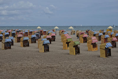 Hooded chairs on beach against sky