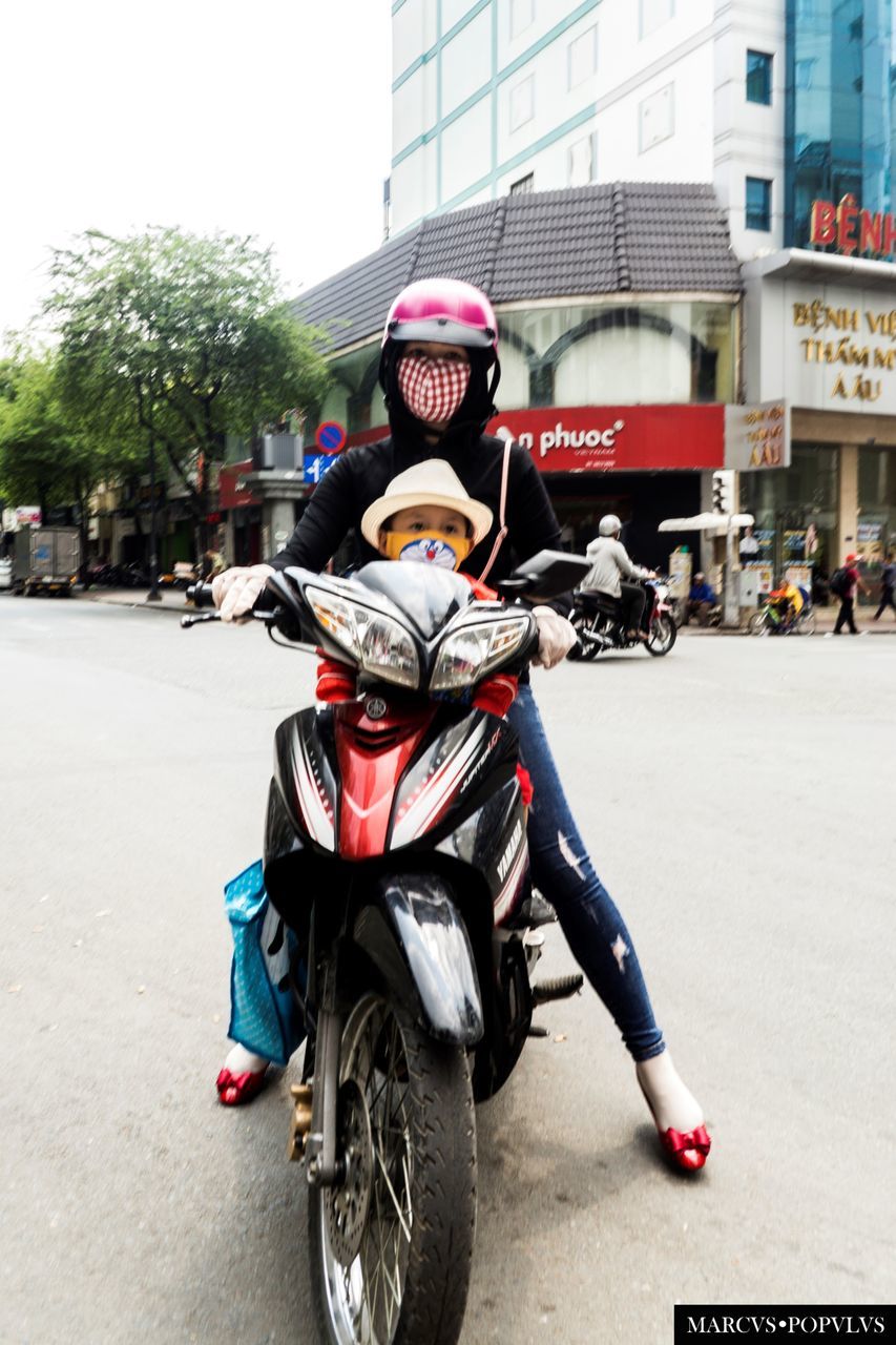 motorcycle, riding, transportation, land vehicle, helmet, architecture, street, building exterior, mode of transport, scooter, outdoors, real people, built structure, headwear, lifestyles, day, bicycle, city, road, men, people