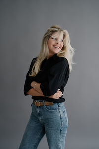 Portrait of young woman standing against wall