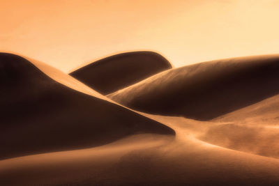 Sand dunes in desert against sky during sunset