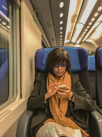 Full length of woman sitting in train