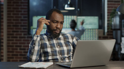 Businessman brainstorming while looking at laptop at office