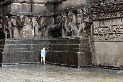 Man standing by statue against historic building