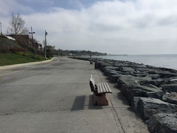 Empty road by sea against sky