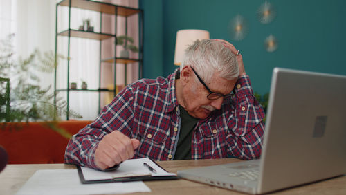 Side view of man using laptop at table