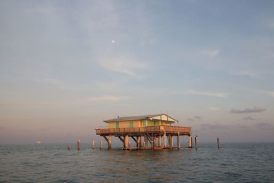 Pier over sea against sky during sunset