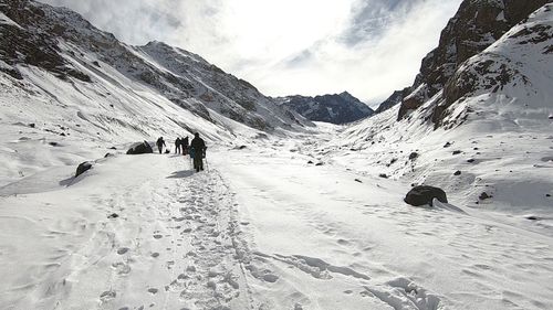 Rear view of people on snowcapped mountains against sky