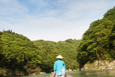 Rear view of woman traveling in boat on lake against sky