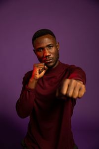 Portrait of young man standing against gray background