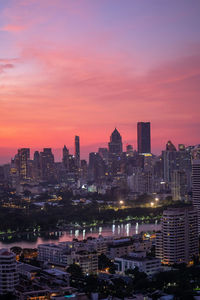 Illuminated cityscape against sky during sunset