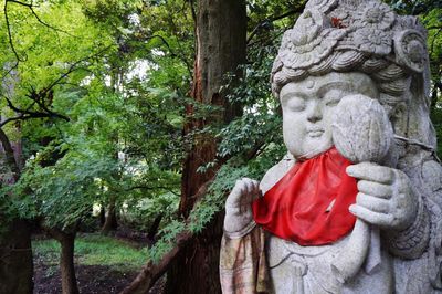 Statue by tree trunk