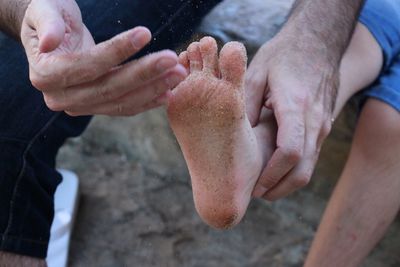 Man cleaning boy's sandy feet