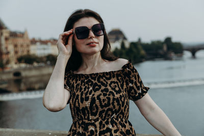 A young brunette girl stands on a bridge on a summer day.