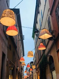 Low angle view of lanterns hanging by buildings against sky