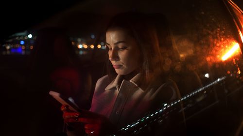 Serious businesswoman using smartphone in driver sits while riding from work