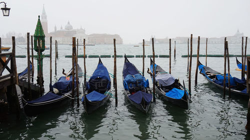 Boats moored in canal against sky