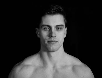 Portrait of shirtless man against black background