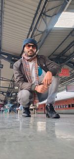 Portrait of young man crouching on station platform