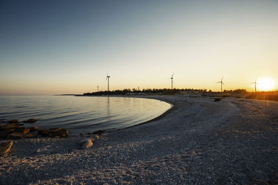 Beach at sunset, wind turbines on background