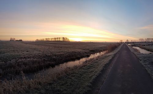 Panoramic view of road on field against sky during sunset