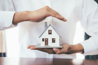 Midsection of man holding illuminated house in building