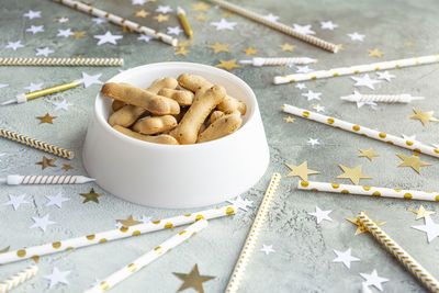 Dog's birthday treat in white bowl on festive green background with stars.
