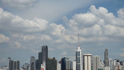 Buildings in city against cloudy sky