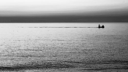 Silhouette person in sea against sky