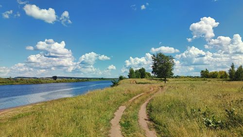 Panoramic view of road amidst field against sky