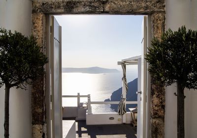 Chairs and table by sea against clear sky seen through window