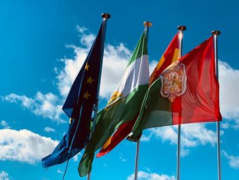 Low angle view of various flags against blue sky