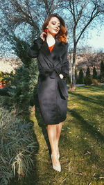 Portrait of smiling young woman standing in park