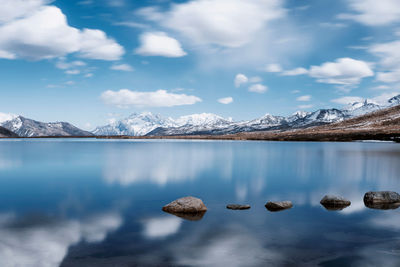 Scenic view of lake and snowcapped mountains against cloudy sky