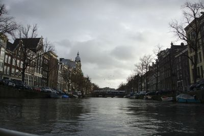 Canal amidst buildings in city against sky