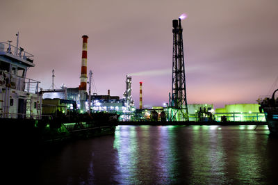 Illuminated cranes at harbor against sky